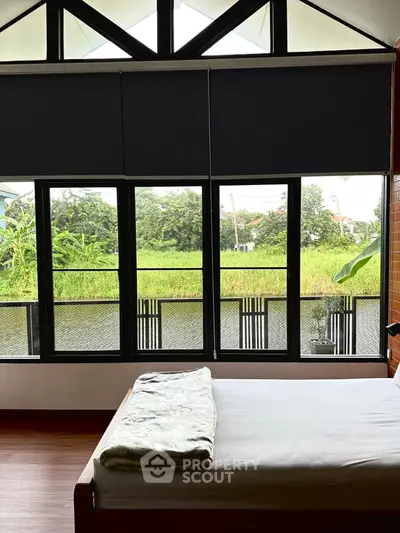 Cozy bedroom with large windows offering serene garden view