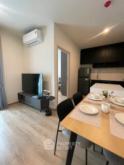 Modern open-plan living room with dining area and kitchen, featuring sleek furniture and appliances.