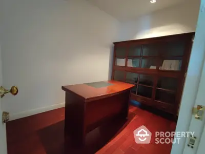 Spacious study room with polished hardwood floors and built-in wooden bookshelves, perfect for a home office setup.