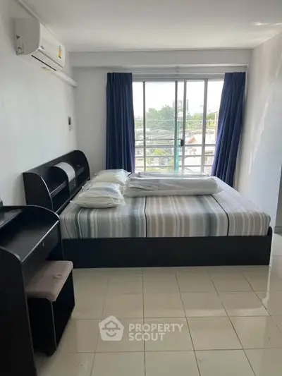 Bright bedroom with large window and modern furnishings in a stylish apartment.