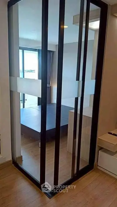 Modern bedroom with sliding glass doors and wooden flooring, offering a sleek and contemporary design.