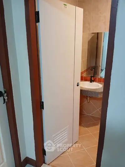Compact bathroom with modern fixtures and tiled walls, featuring a sleek vanity and mirror.