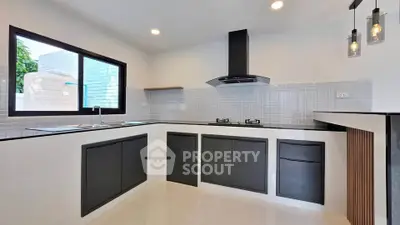 Modern kitchen with sleek black cabinets and gas stove, featuring a minimalist design and ample natural light.