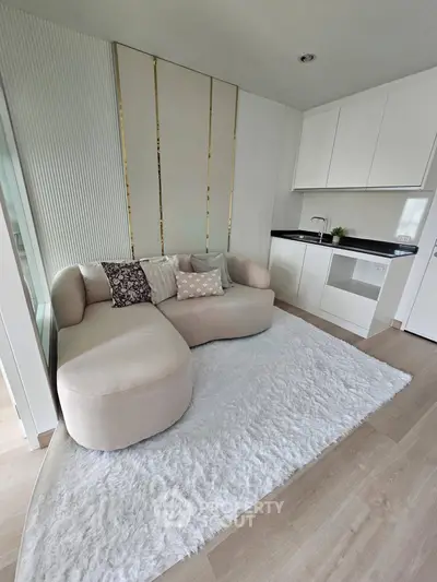 Chic modern living room with plush sofa and sleek kitchenette, perfect for cozy urban living.