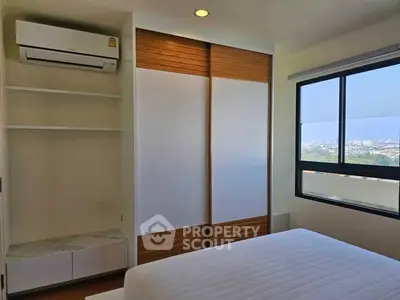 Modern bedroom with city view, featuring built-in closet and air conditioning.
