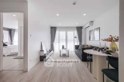 Modern living room with stylish decor and open layout leading to a cozy bedroom.
