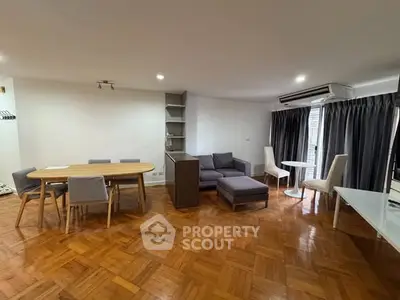 Spacious living room with parquet flooring and modern furniture in a well-lit apartment.