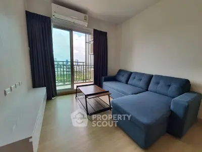 Modern living room with blue sectional sofa and city view balcony in high-rise apartment.