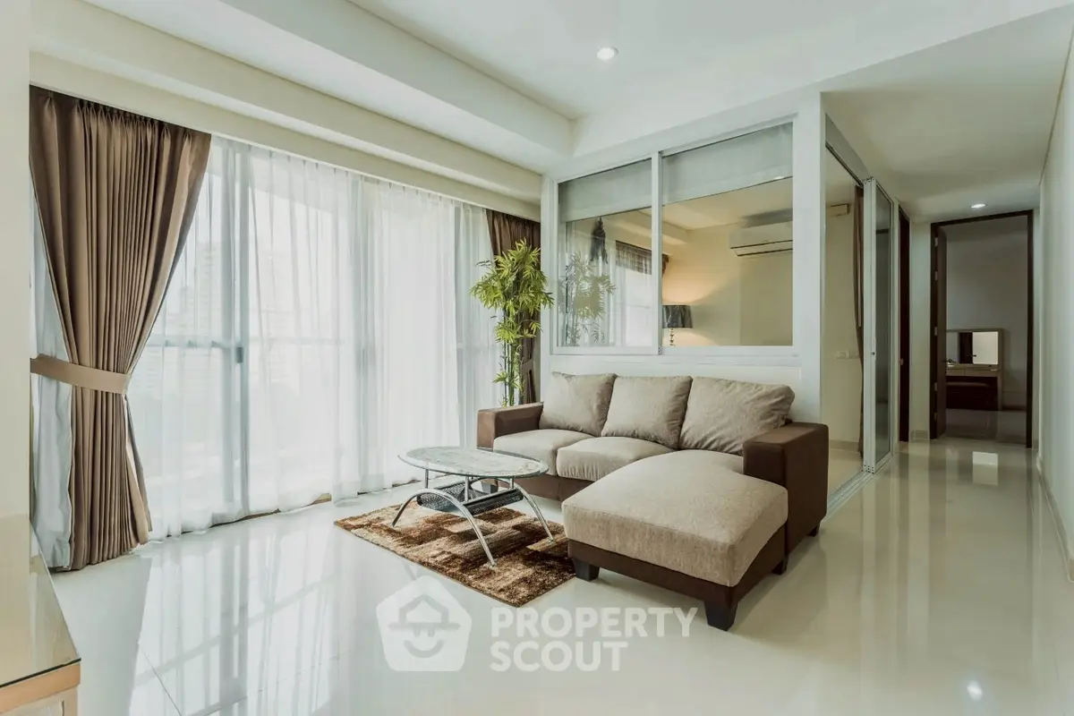 Spacious modern living room with large windows and elegant decor in a high-rise apartment.