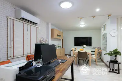 Spacious open-plan living area with modern kitchen, large dining table, and cozy workspace, featuring bright lighting and chic white brick walls.