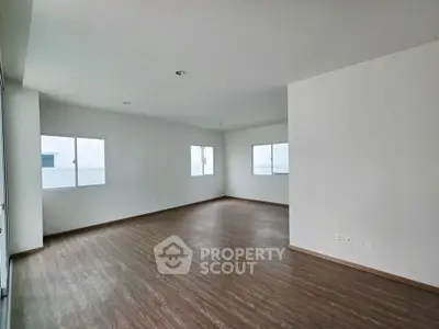 Spacious empty room with large windows and wooden flooring, ideal for customization.