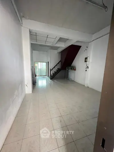 Spacious interior with tiled flooring and staircase in a real estate property.
