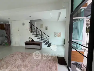 Spacious modern living room with staircase and large windows, offering abundant natural light and open layout.