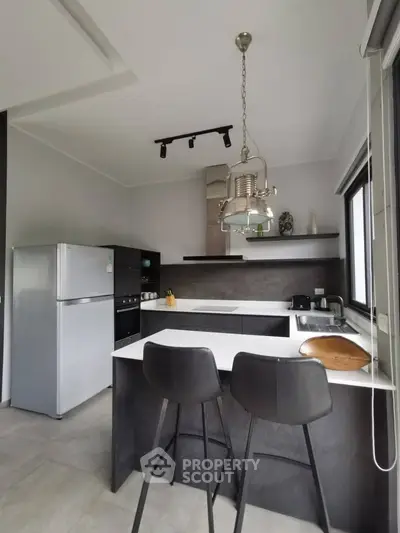 Modern kitchen with sleek design, featuring a breakfast bar and stainless steel appliances.