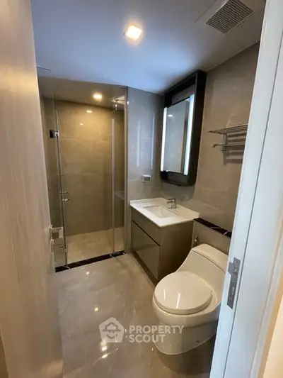 Modern bathroom with sleek fixtures and glass shower enclosure in a contemporary apartment.
