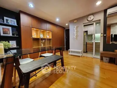 Modern dining area with glass table and wooden cabinetry in stylish apartment.