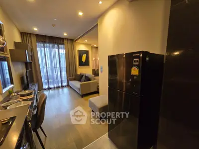 Modern open-layout living room with kitchen, featuring sleek furniture and large windows for natural light.
