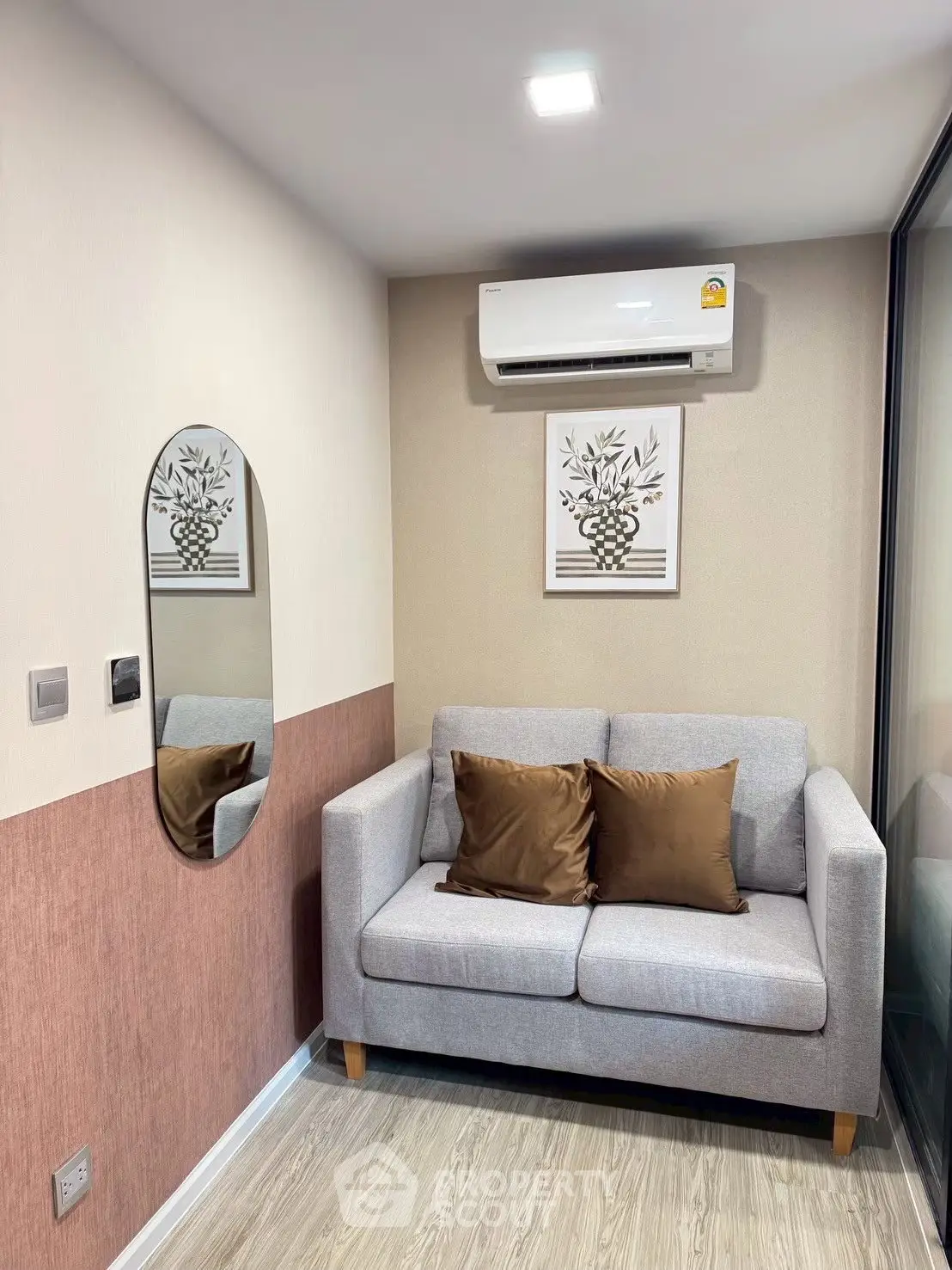 Cozy living room with modern sofa and wall art, featuring air conditioning and stylish decor.