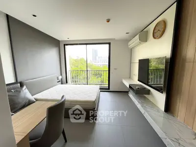 Modern bedroom with balcony view, sleek furniture, and wall-mounted TV in a stylish apartment.