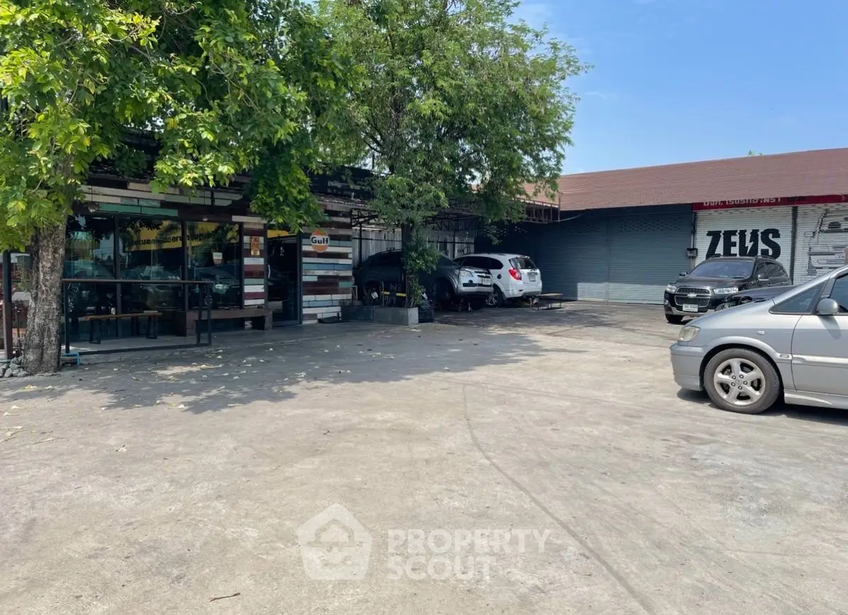 Spacious parking area with multiple cars and a tree-shaded entrance, ideal for commercial use.