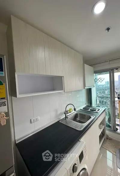 Modern kitchen with sleek cabinetry, dual sinks, and city view from window.