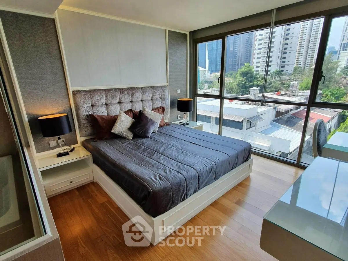 Luxurious bedroom with city view, featuring modern decor and large windows for natural light.