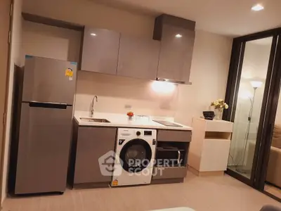 Modern kitchen with sleek cabinets, washing machine, and fridge in a cozy apartment setting.