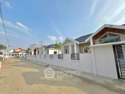 Charming suburban street with modern single-story homes and gated entrances under a clear blue sky.