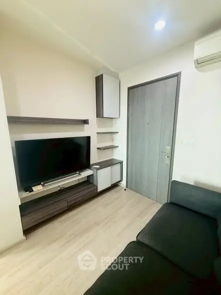 Modern living room with sleek furniture and wall-mounted TV in a cozy apartment.