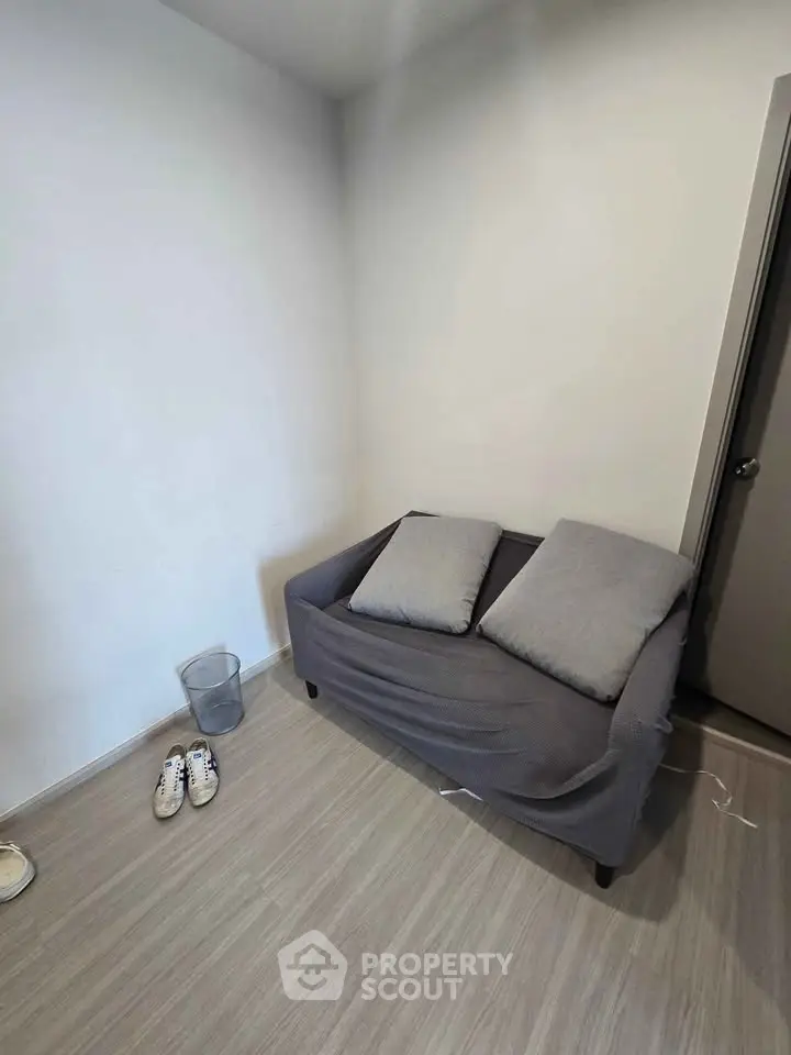 Cozy minimalist room with a small sofa, perfect for a compact living space.