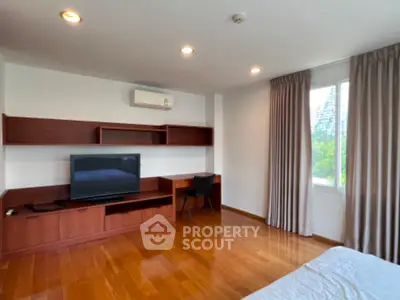Spacious bedroom with wooden flooring and modern TV setup