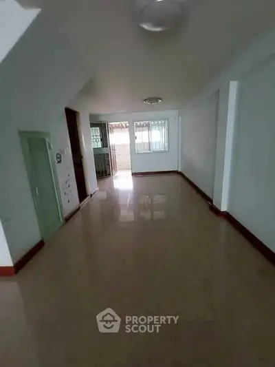 Spacious empty room with glossy tiled floor and natural light