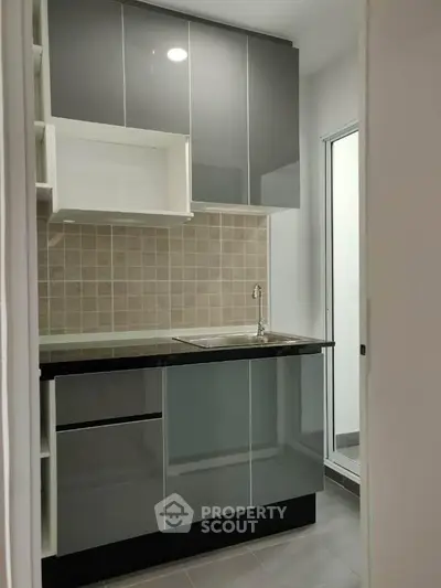 Modern compact kitchen with sleek cabinetry and tiled backsplash