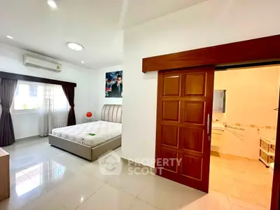 Spacious bedroom with modern design and ensuite bathroom, featuring large windows and sleek finishes.