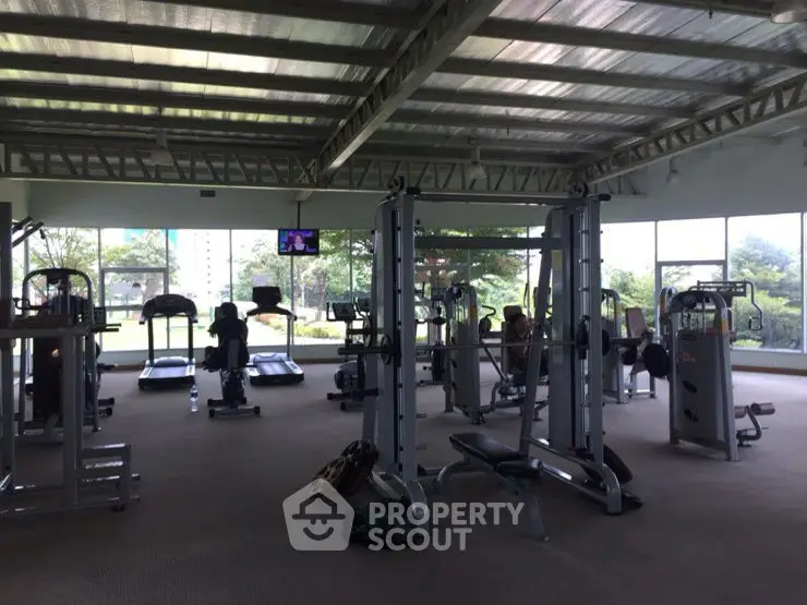 Spacious gym with modern equipment and large windows offering garden views.
