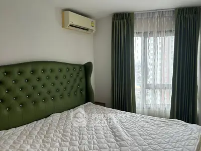 Cozy bedroom with green upholstered headboard and air conditioning, featuring a large window with city view.