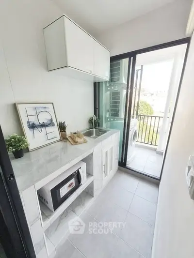 Modern kitchen with sleek design and balcony view, featuring built-in microwave and stylish decor.