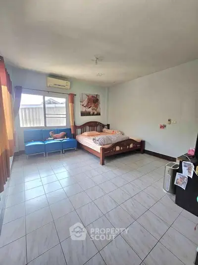 Spacious bedroom with large window and cozy seating area, perfect for relaxation.