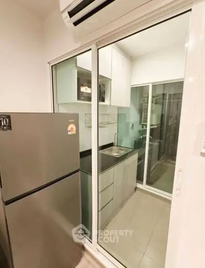 Modern kitchen with sleek cabinetry and stainless steel fridge in compact layout.