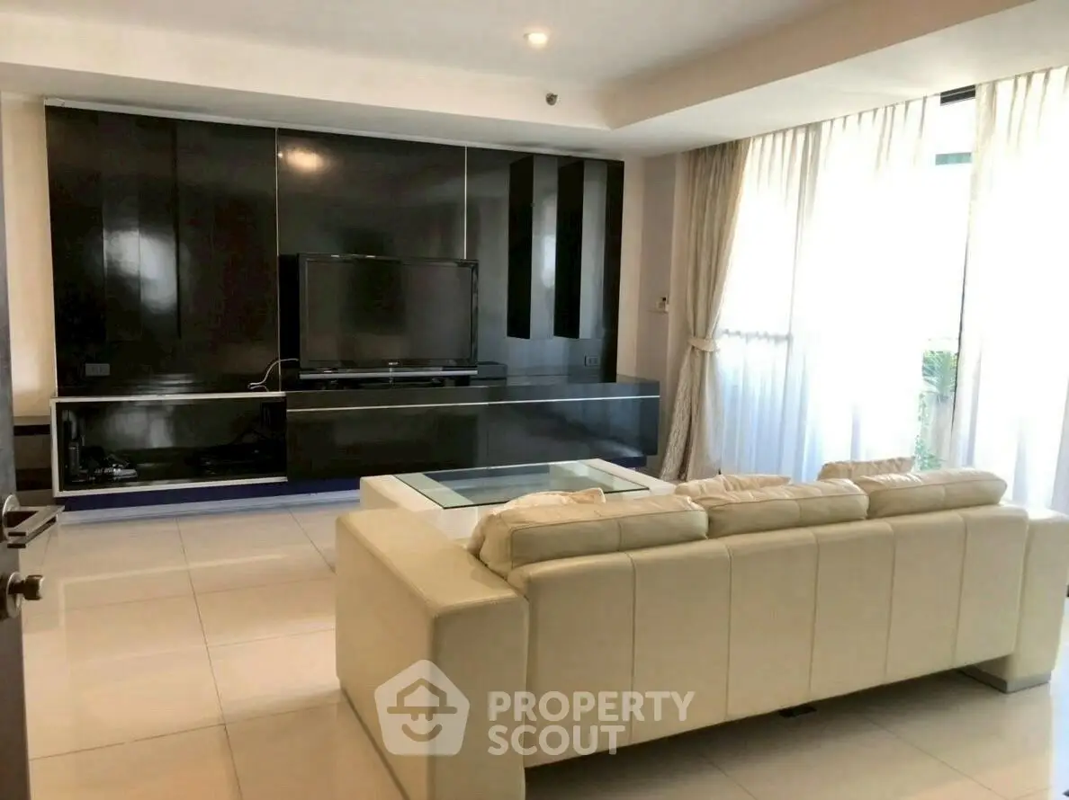 Spacious modern living room with sleek black entertainment center and plush beige sofa.