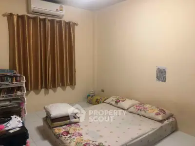 Cozy bedroom with minimalist decor and air conditioning, featuring a simple bed setup and warm lighting.