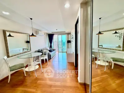 Spacious living room with elegant decor and large mirror, featuring wooden flooring and modern furniture.