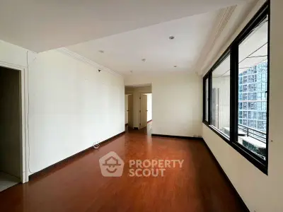 Spacious empty living room with hardwood floors and large windows in modern apartment