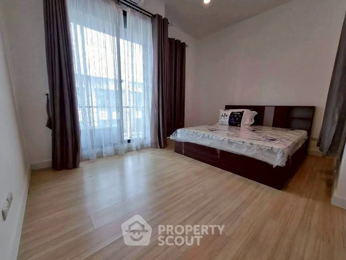 Spacious bedroom with large window and elegant wooden flooring