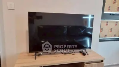 Modern living room with sleek TV setup on wooden stand, perfect for entertainment.