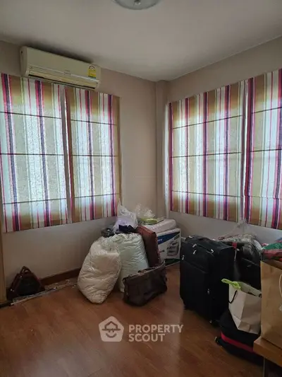 Cozy room with striped curtains and wooden flooring, ideal for storage or small office.