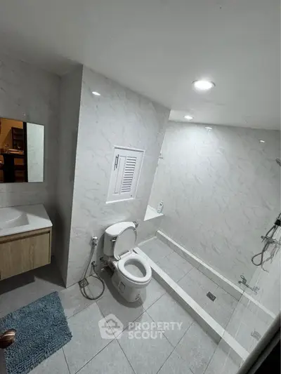 Modern bathroom with sleek design, featuring a glass shower enclosure and elegant fixtures.