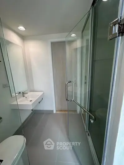 Modern bathroom with glass shower and sleek fixtures in a contemporary home.