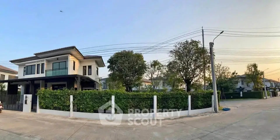 Modern two-story house with lush greenery and corner lot in suburban neighborhood.