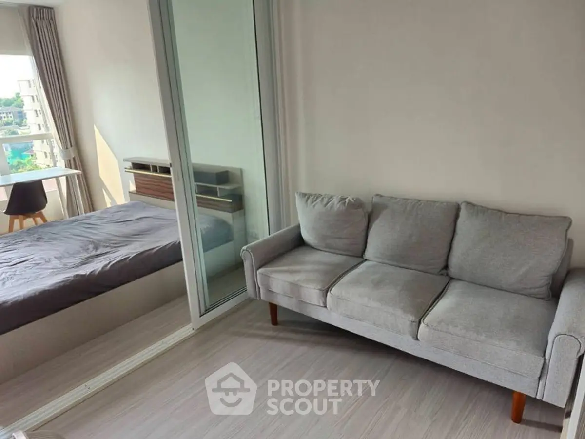 Modern apartment with cozy living room and adjacent bedroom, featuring sleek furniture and natural light.